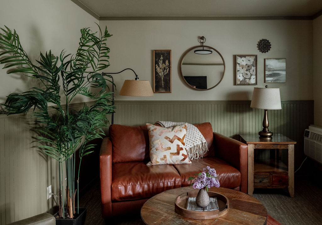 sitting room, red leather love seat, and two brown chairs with coffee table in middle.