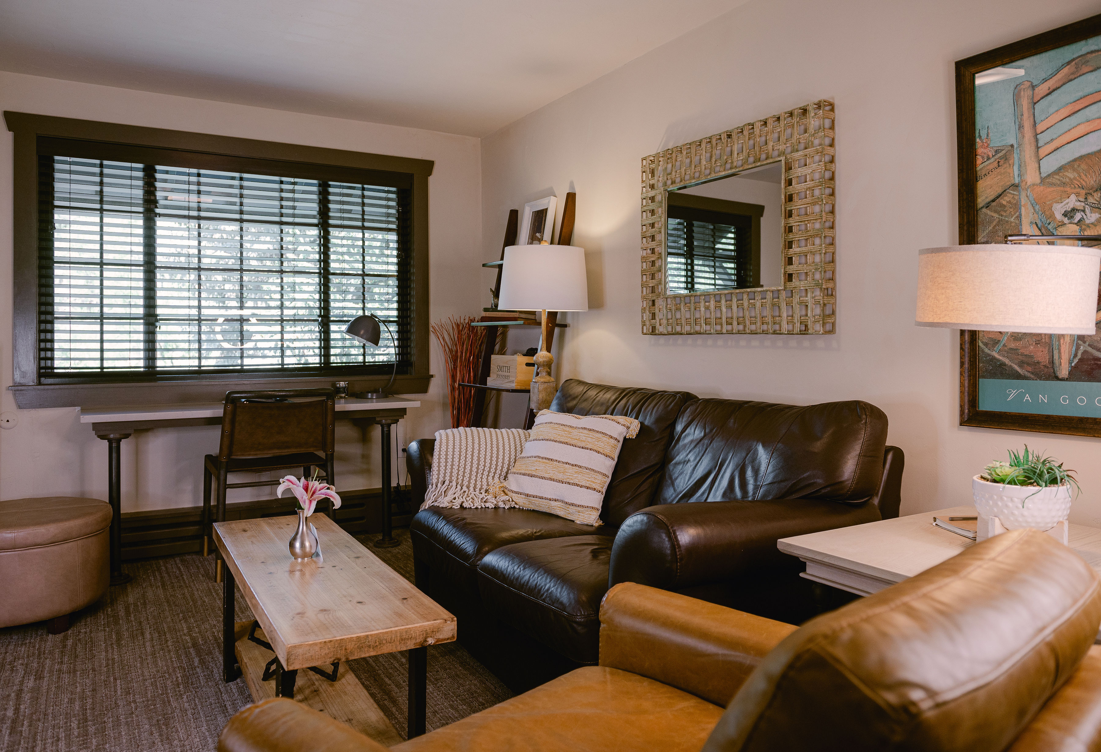 sitting room, black leather love seat, and an armed sitting chair with coffee table in middle.