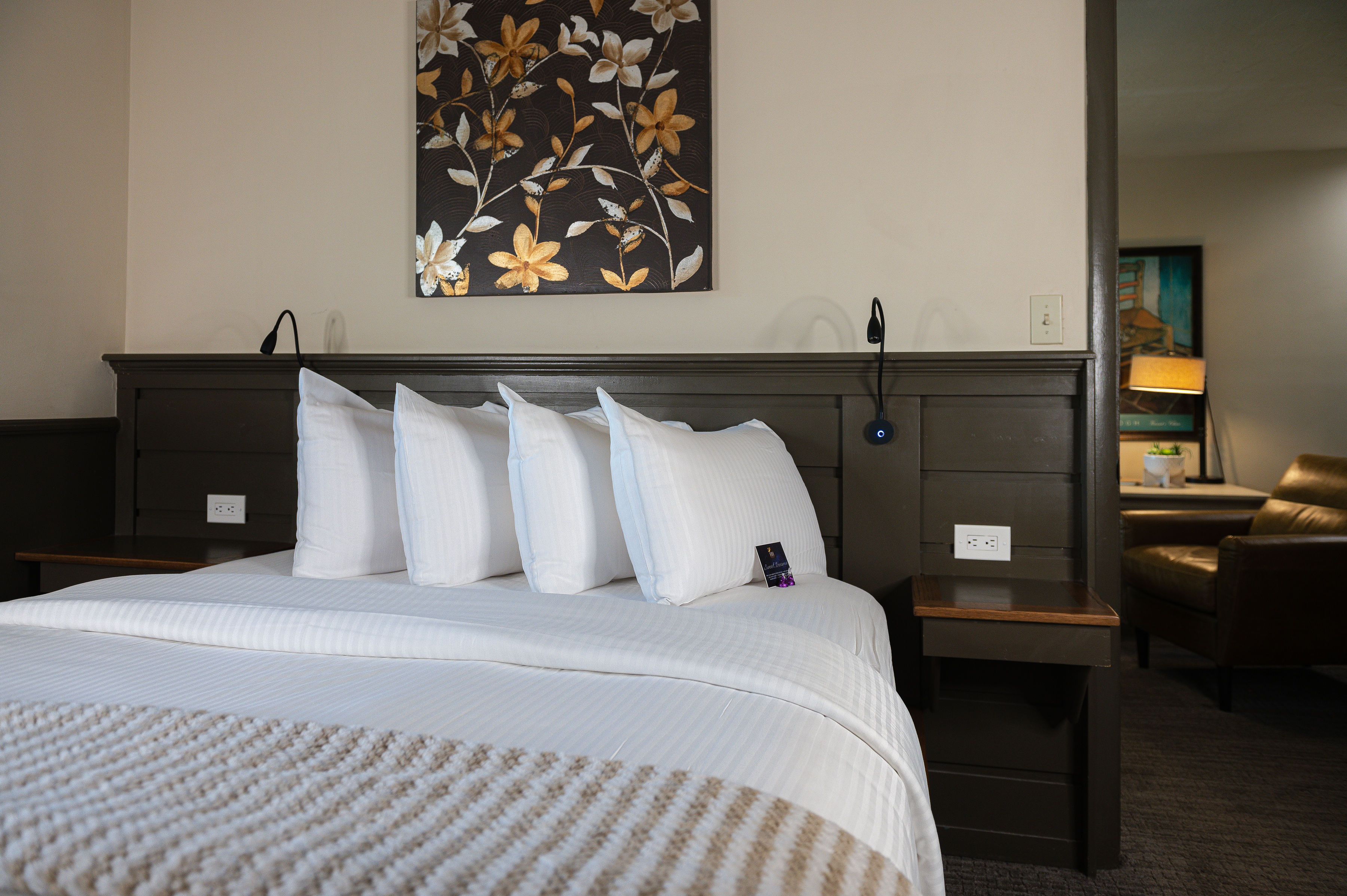 Bedroom with queen bed, cream sitting chair and window