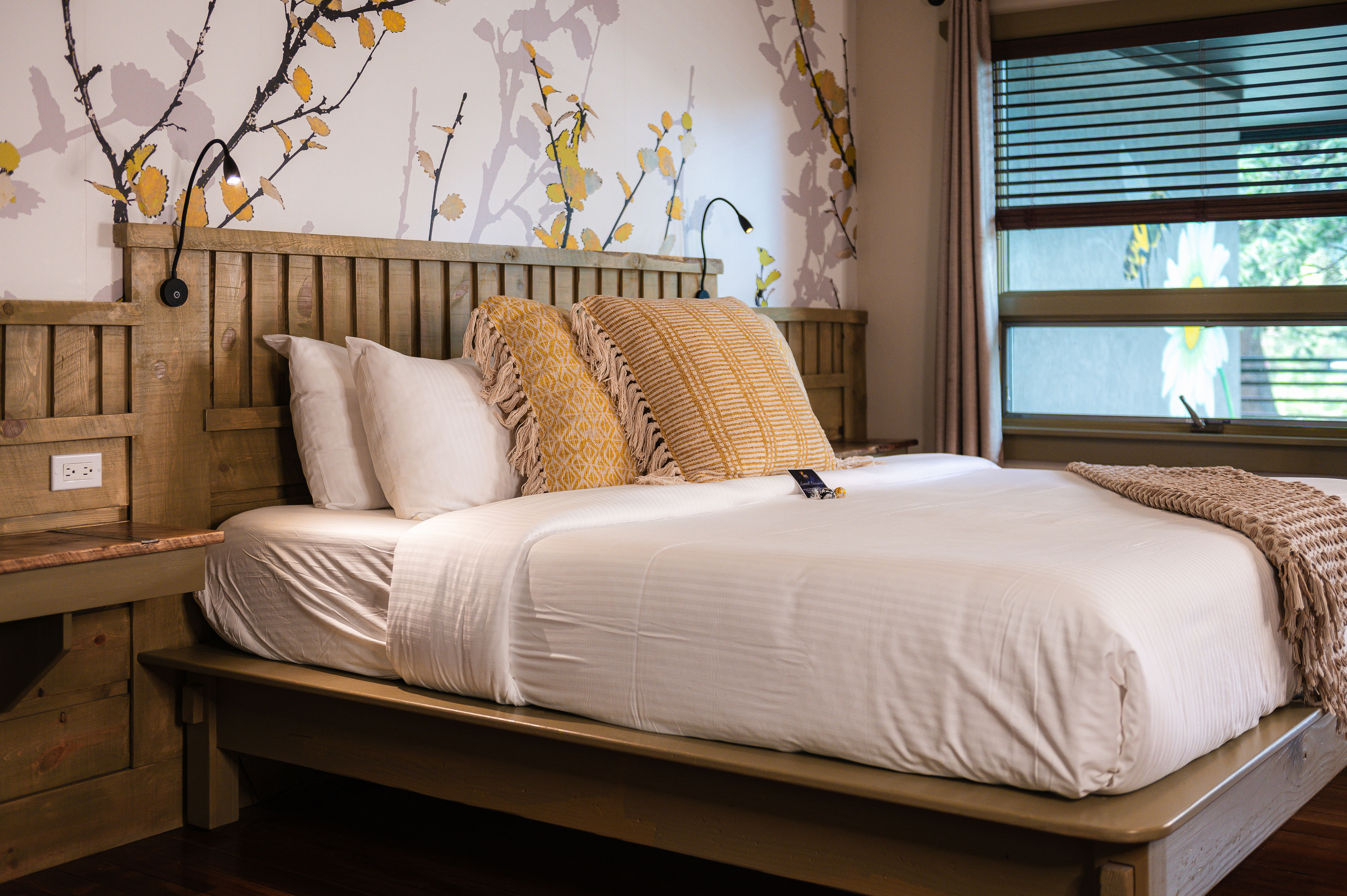 King bed with light colored bedding and textured pillows, two green leather chairs and wood floors