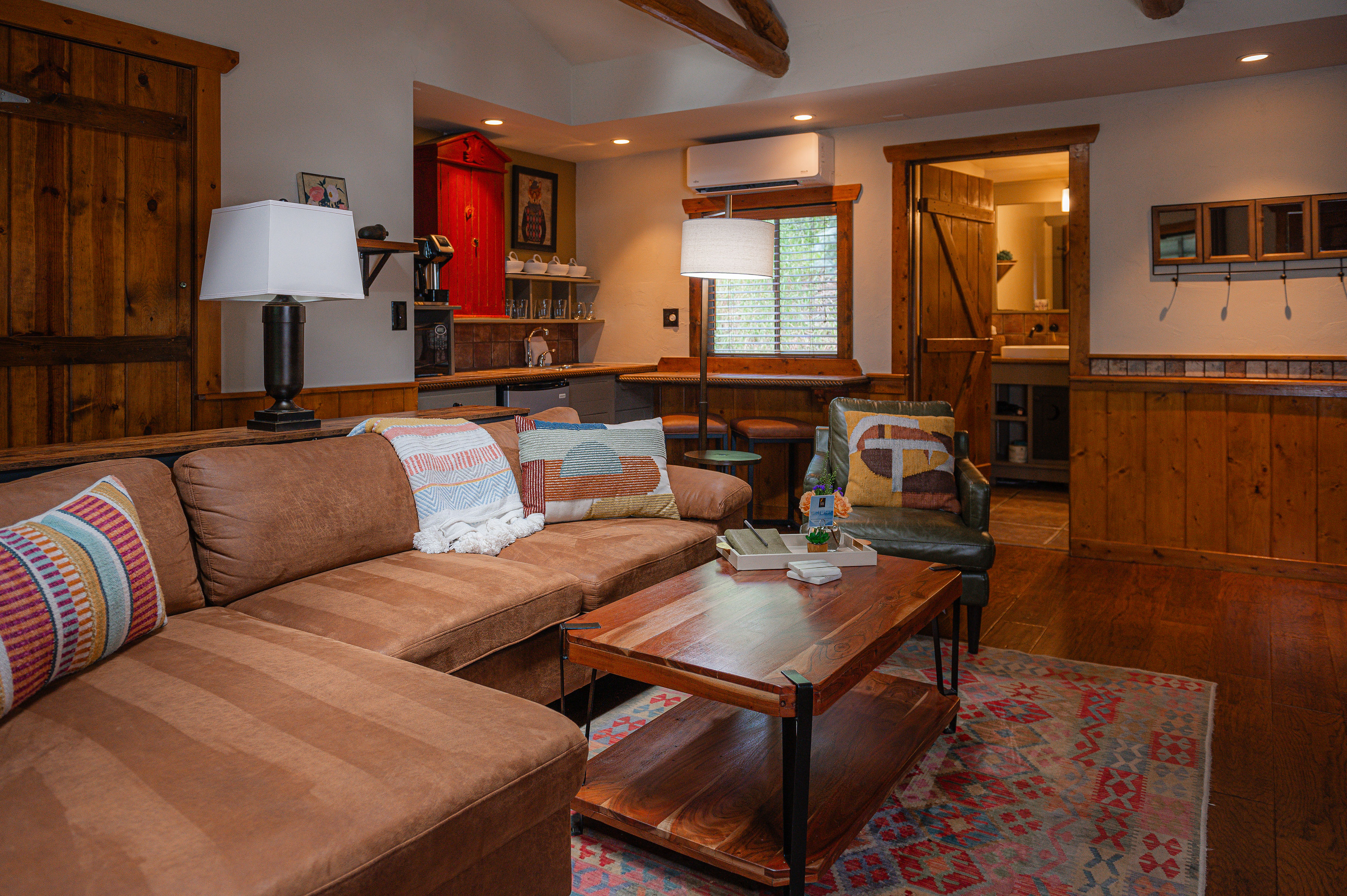 pitched roof with timber beams, brown leather furniture, table and rugf