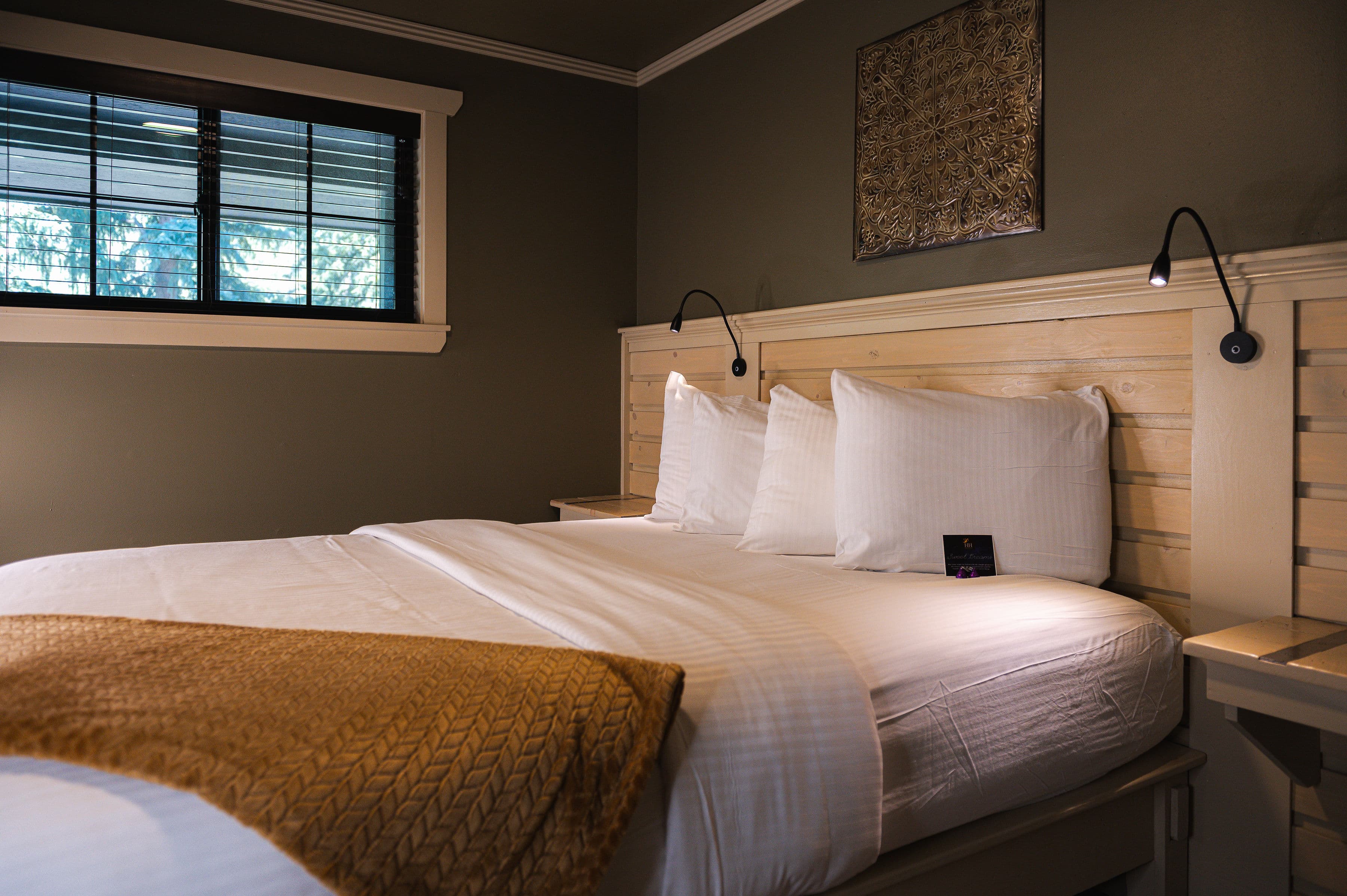 Queen bed with tan blanket.