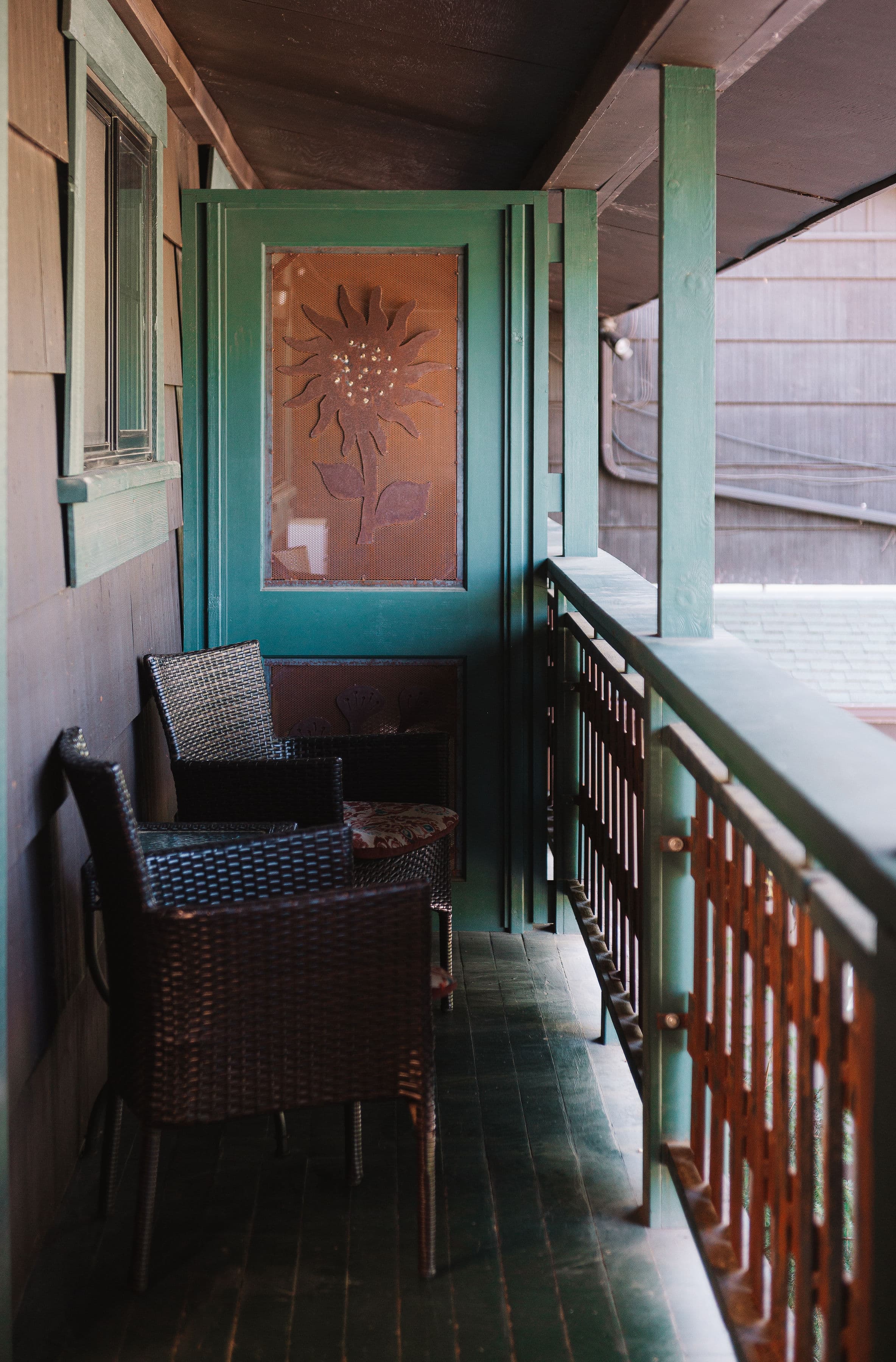 Private balcony with two wicker chairs and small table.