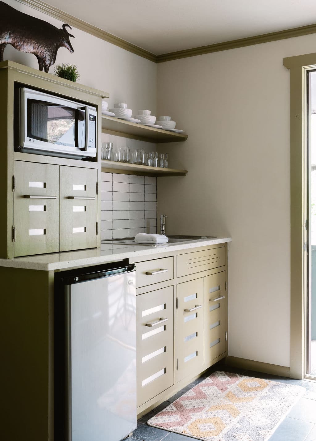 kitchenette with sink, mini-fridge, microwave, coffer maker, cabinets, and shelves with dishware