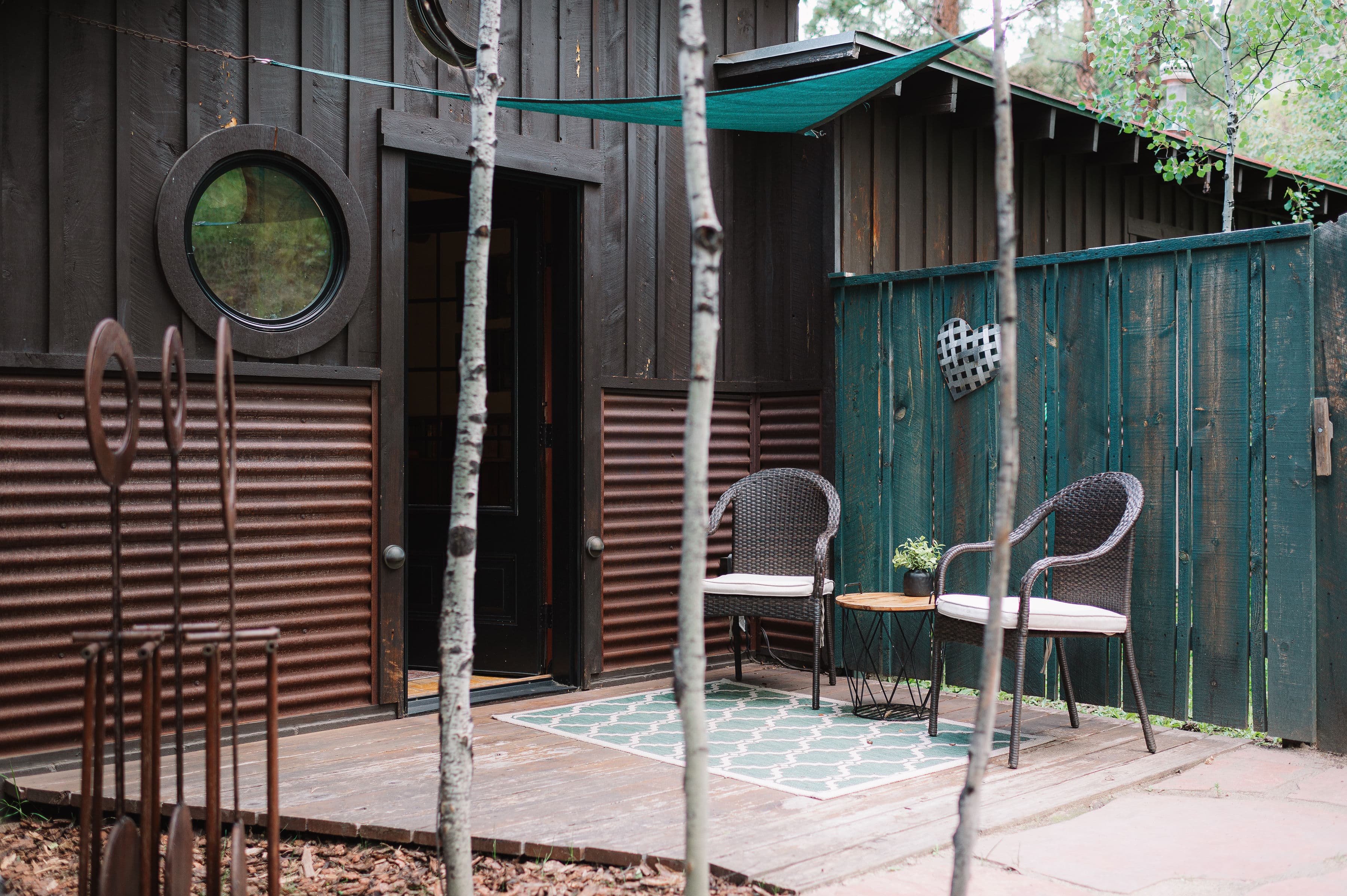 Private outdoor patio with green sun shade, two chairs and a small table