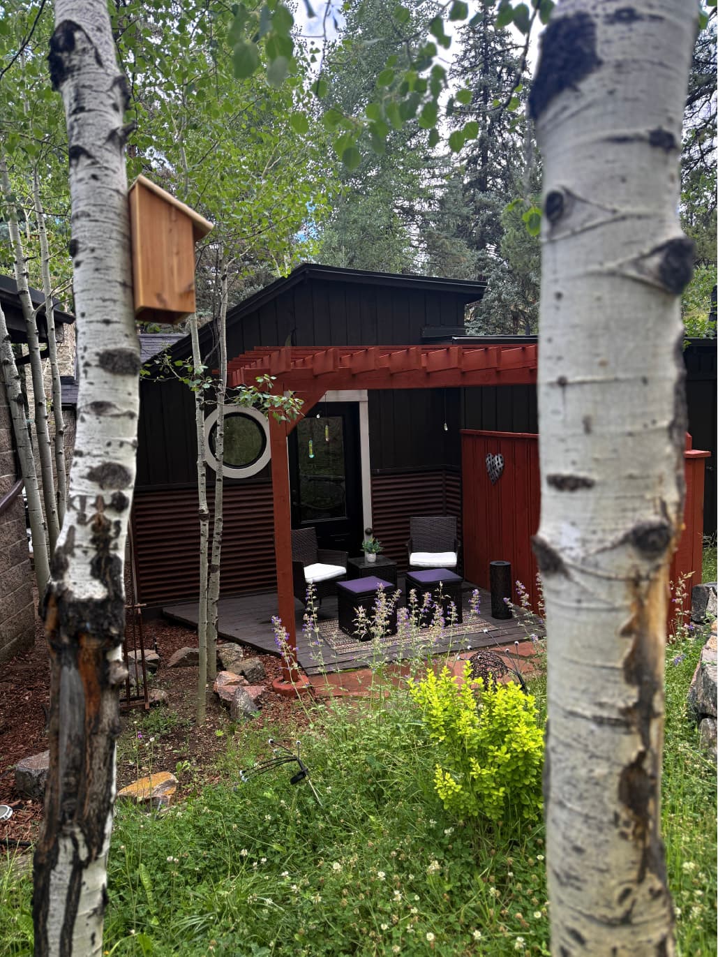 Private outdoor patio with red pergola, two chairs and a small table