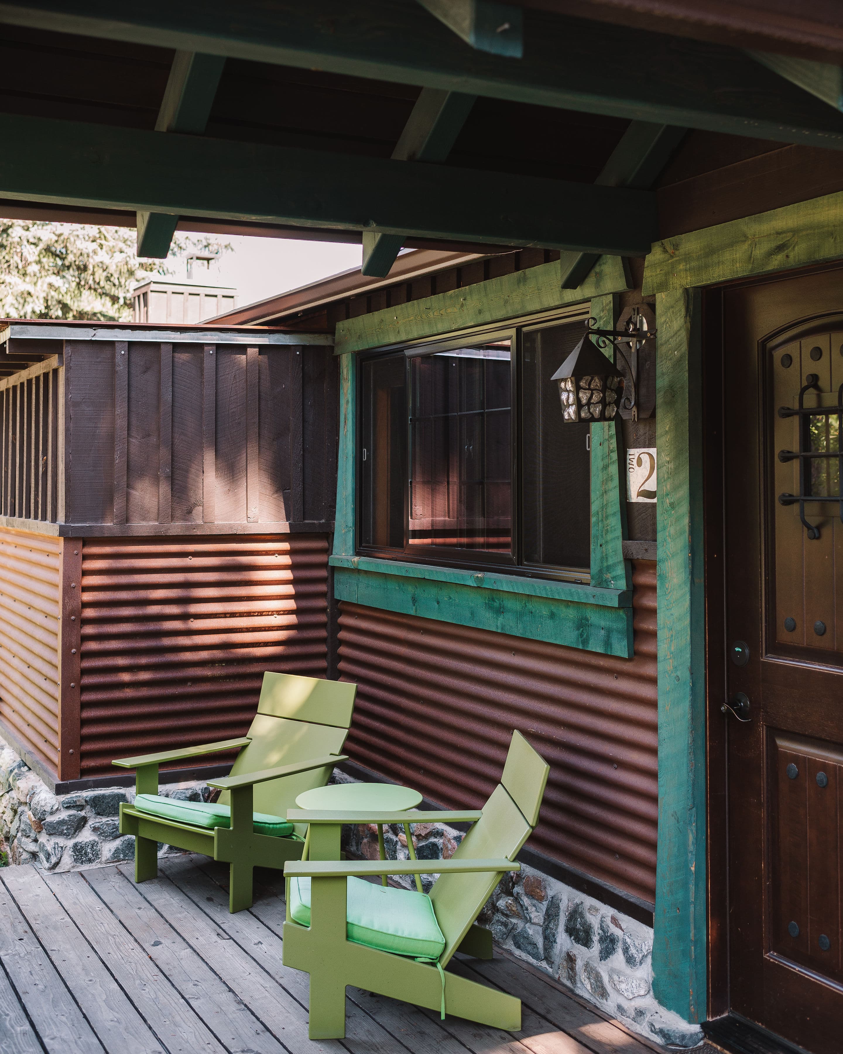 Private outdoor patio with two bright green Adirondak chairs and a small tablet