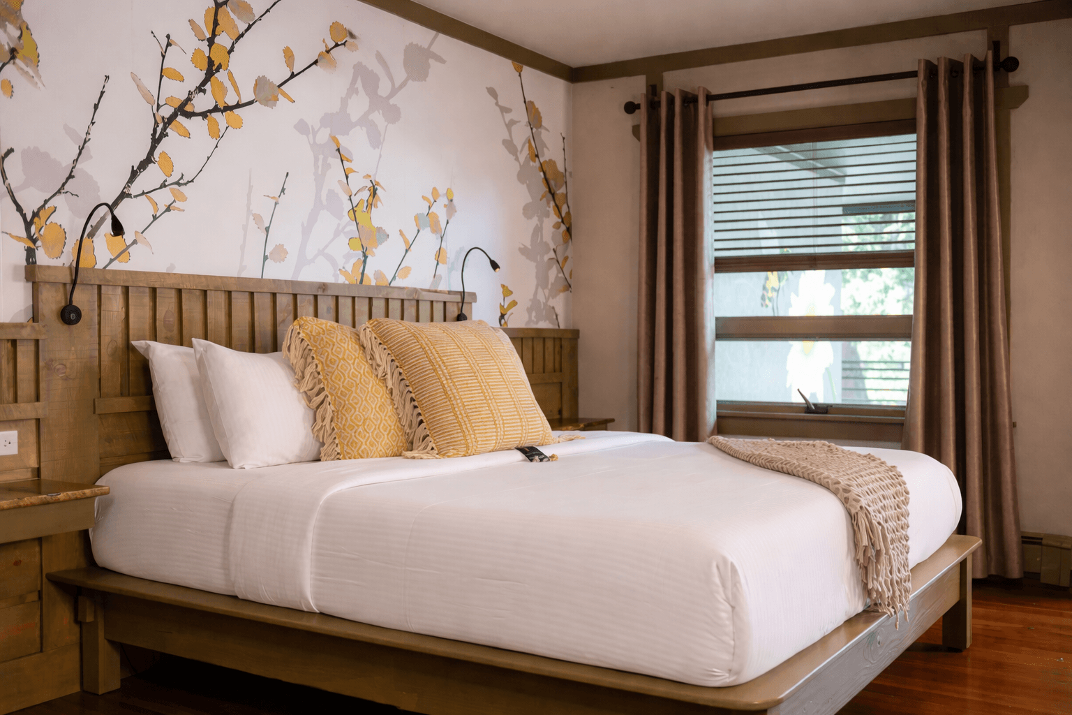 King bed with light colored bedding and textured pillows, two green leather chairs and wood floors