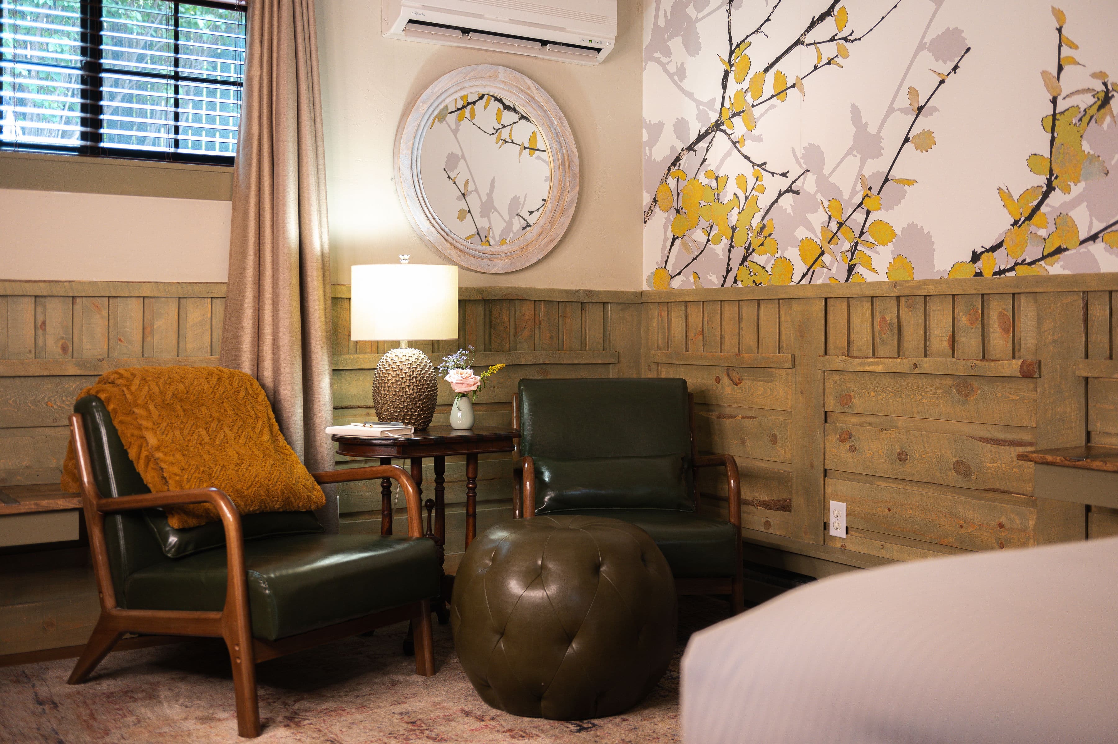 Green leather chairs, green ottoman, small table, air conditioning unit and window