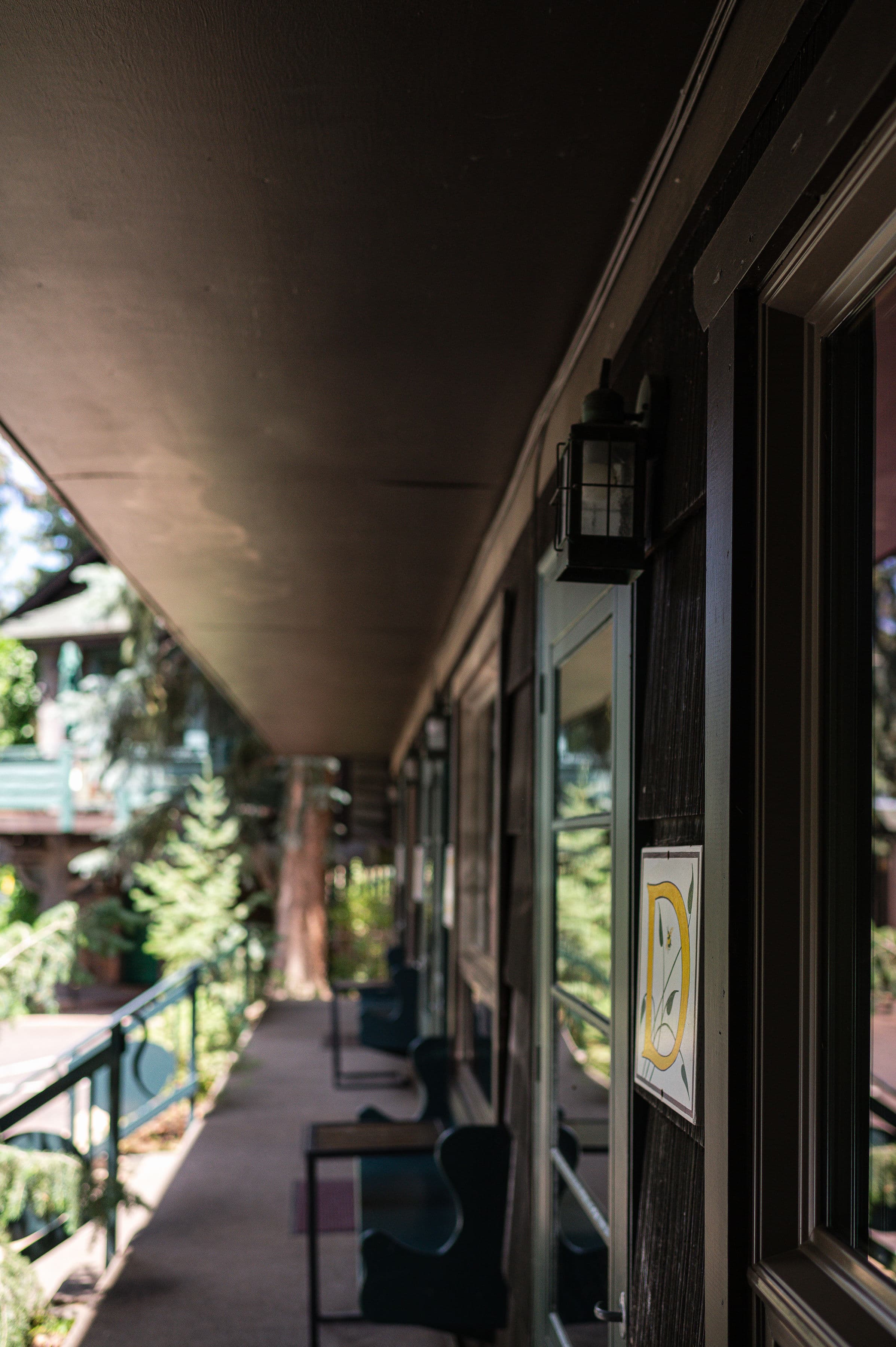 exterior view of guest rooms A, B, and C. Stairs with railings and benches under windows of each room.