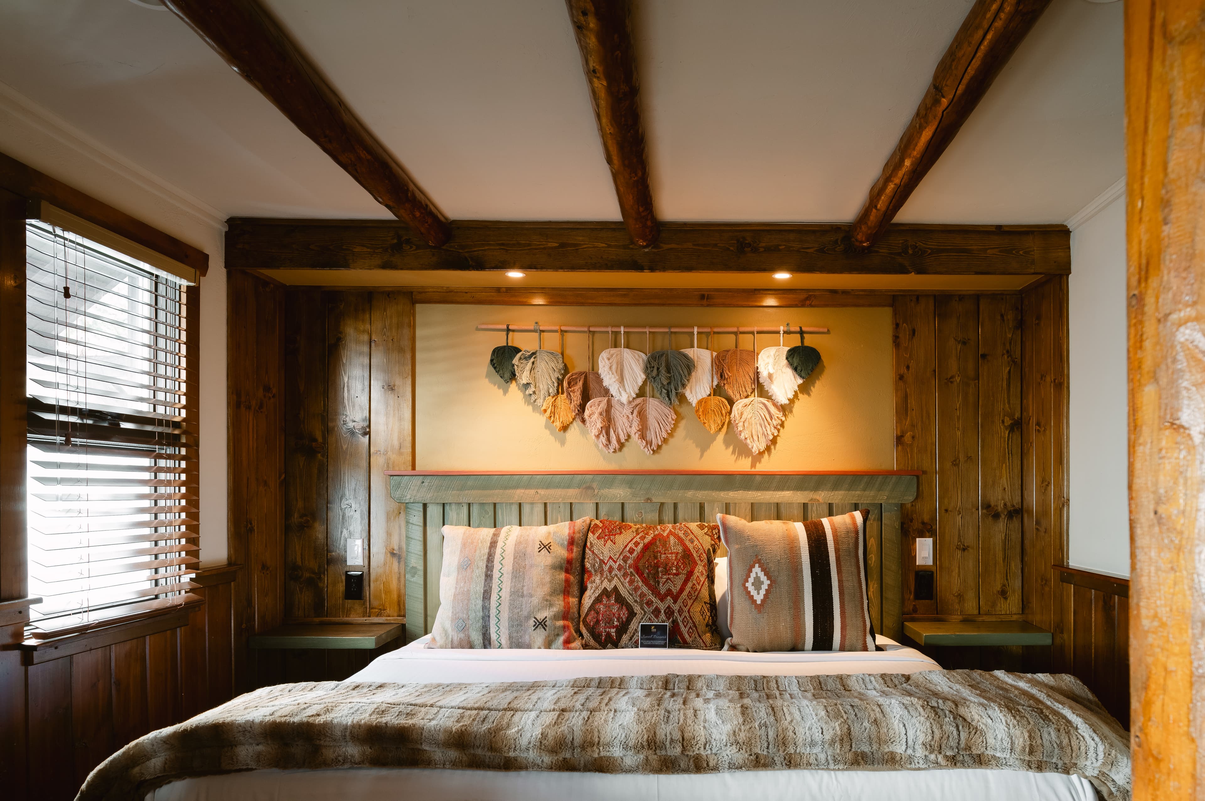 king bed with decorative wall hanging and wood walls