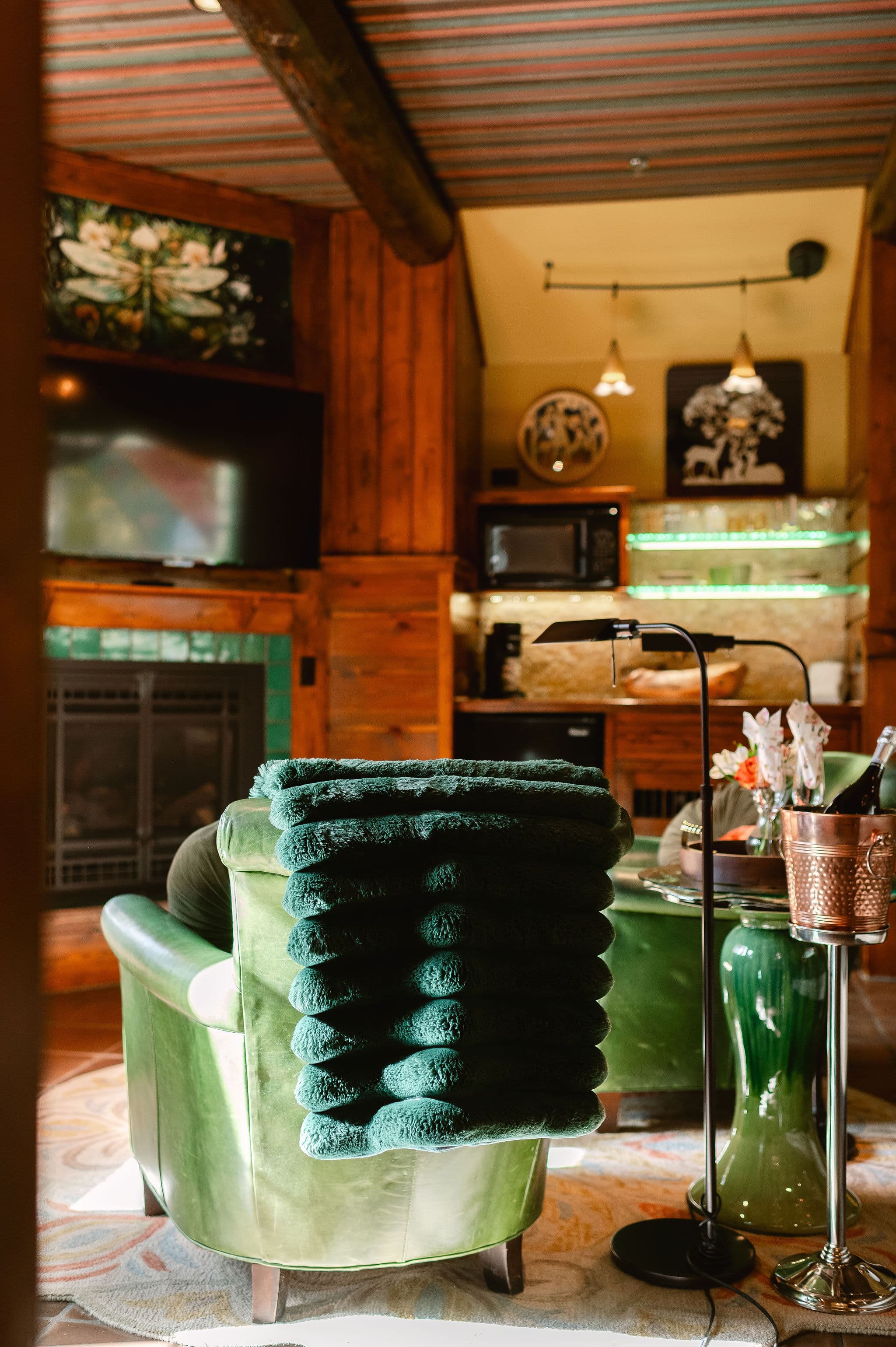 Brown tile floor, green leather chairs, fireplace, wood panel ceiling