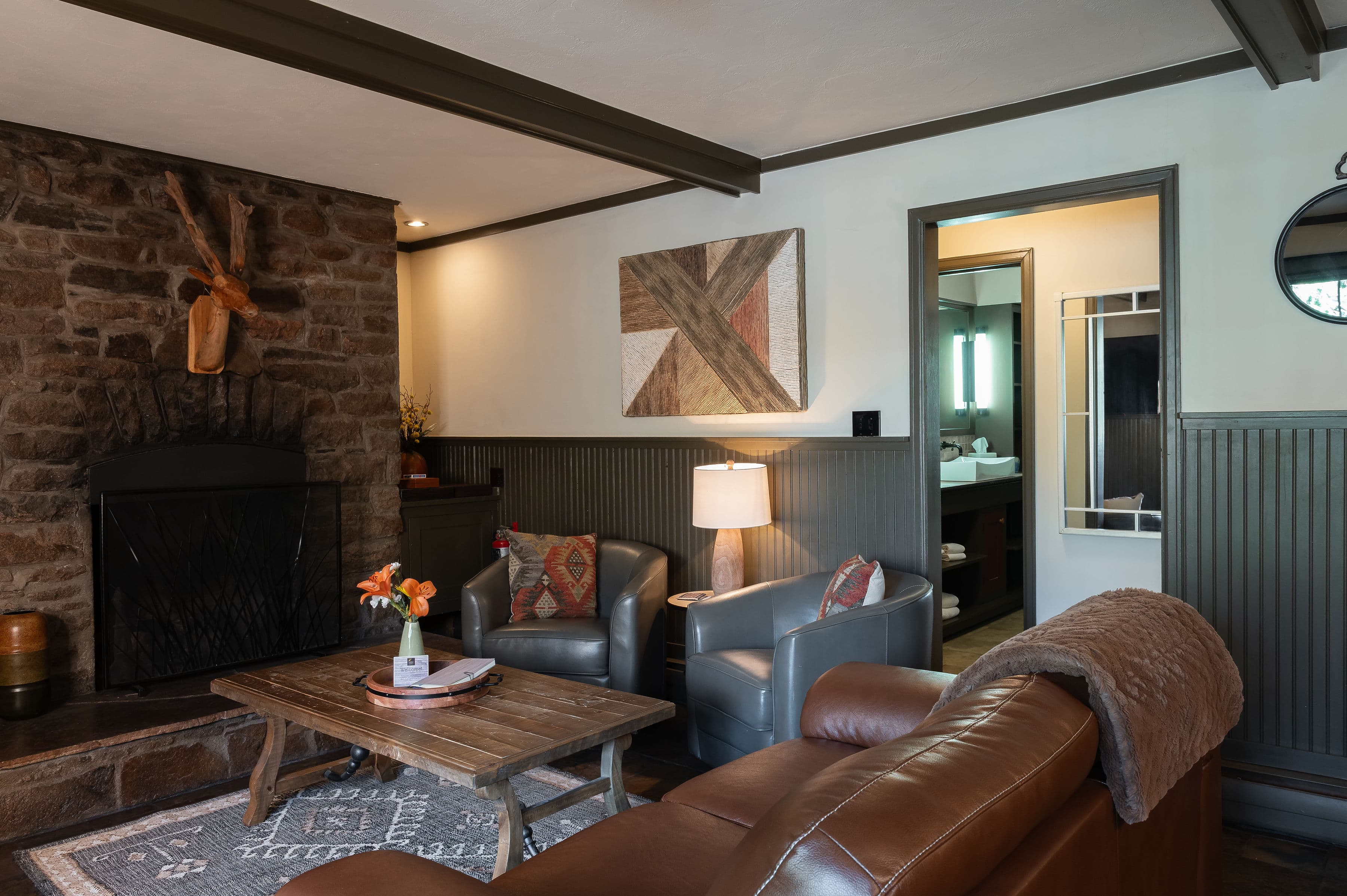 Living room with gas rock fireplace, two swivel chairs, love seat around a coffee table with flat screen tv