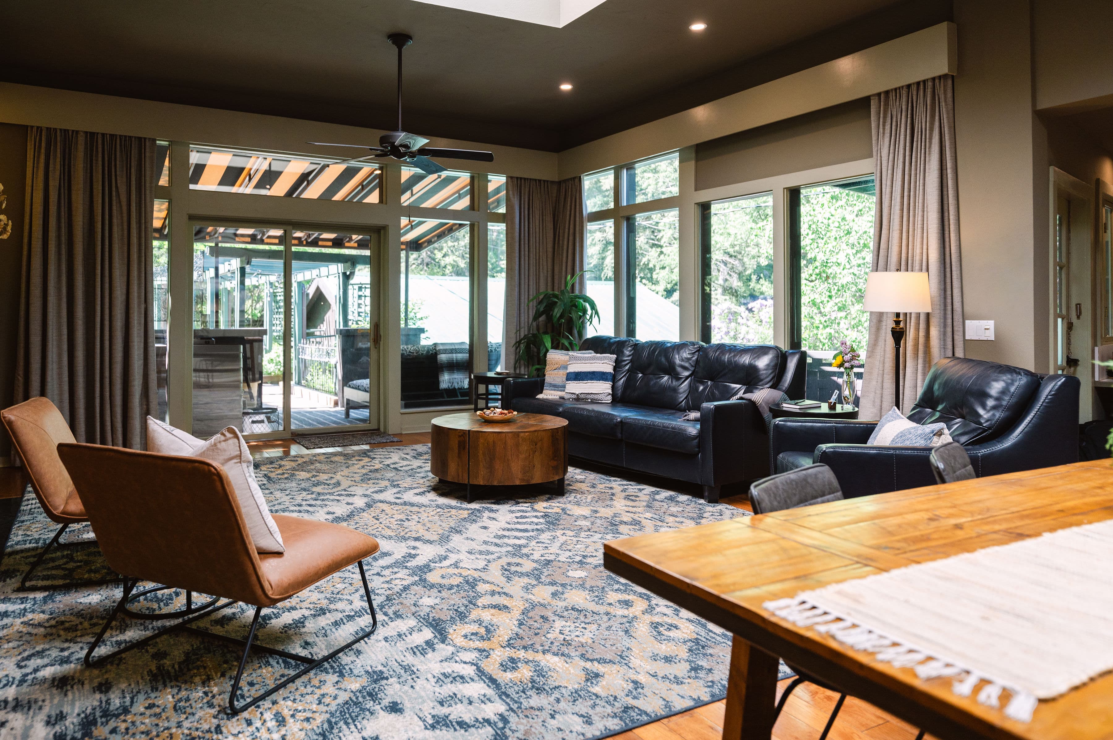 large room with sky lights, wood table, wood floors, fireplace and leather furntiture