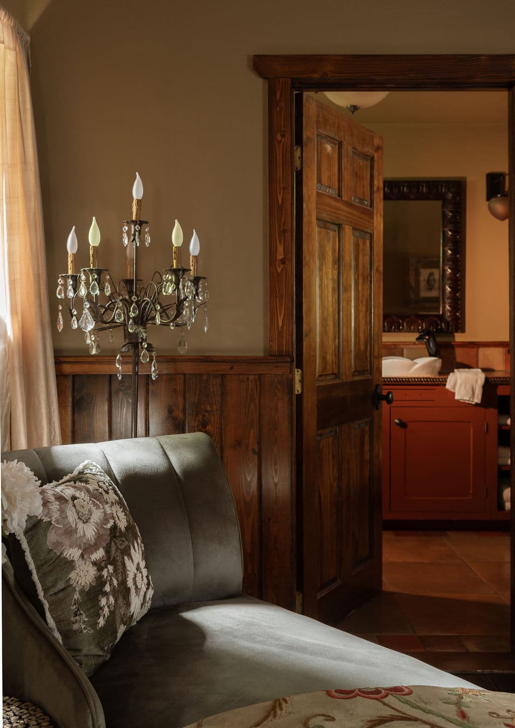 lounge area with velveteen chaise, open concept closet and standing chandelier.