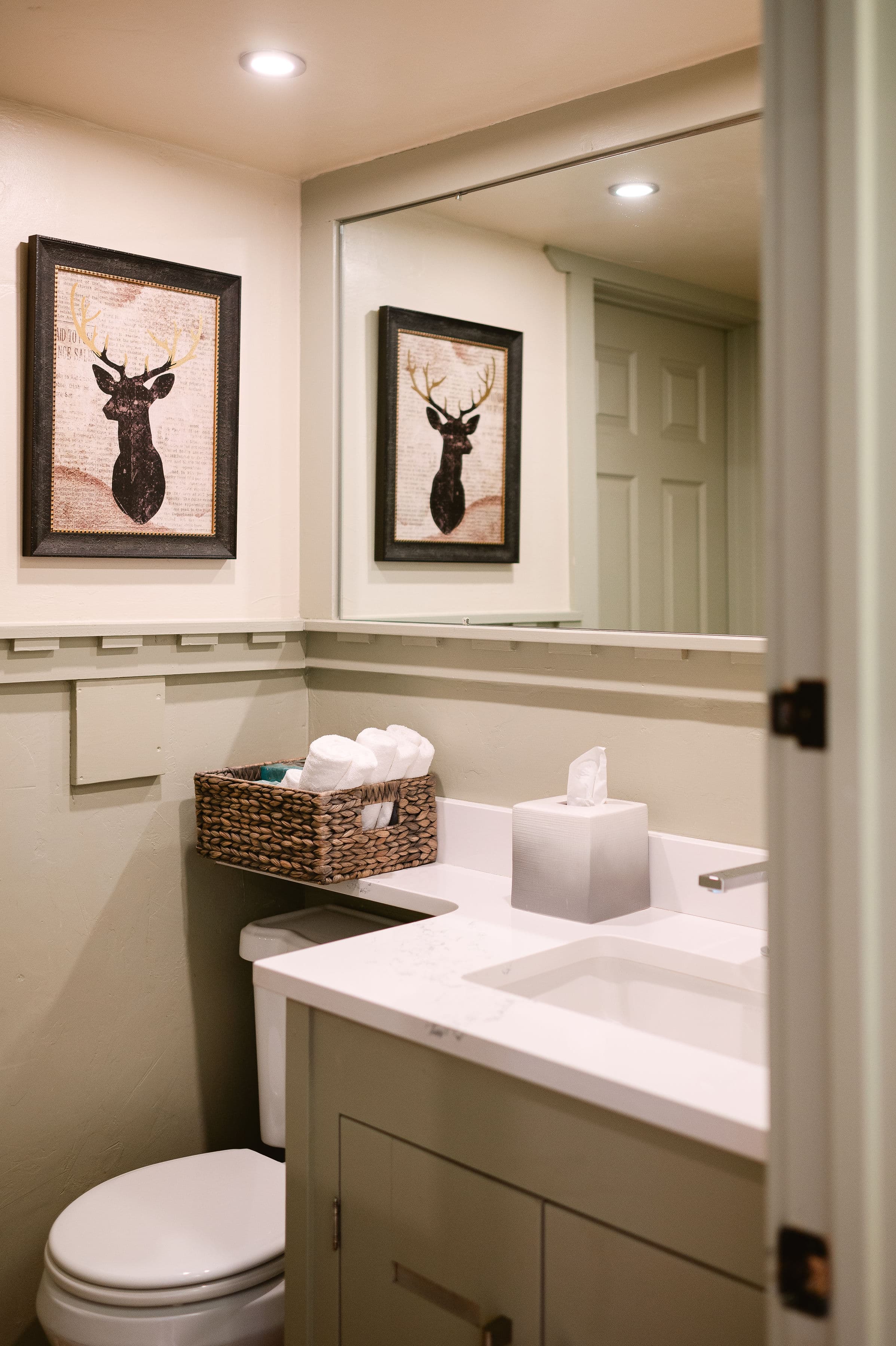 A stylish bathroom featuring deer-themed artwork, a modern sink, and neatly arranged toiletries.