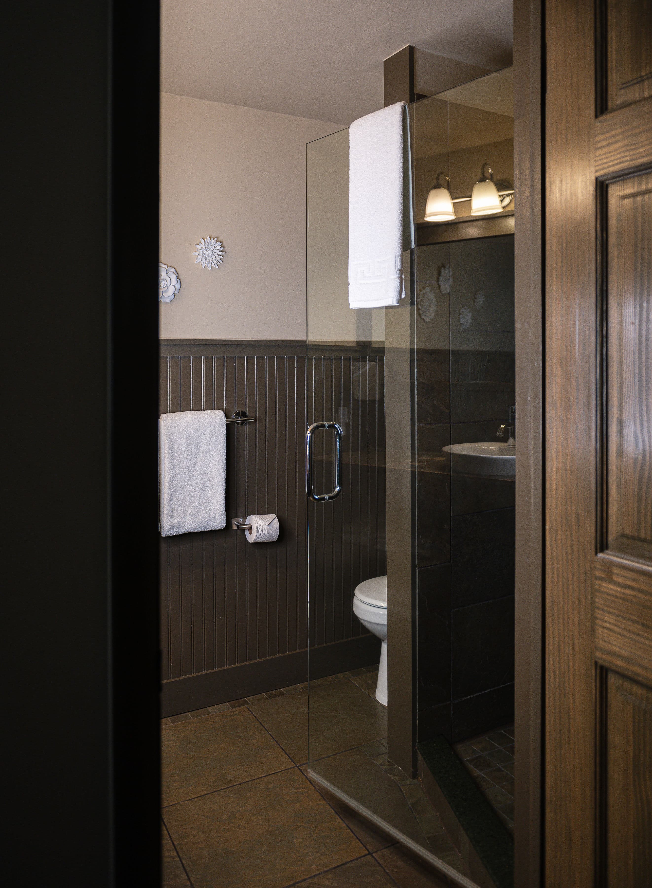 A modern bathroom featuring a glass shower, towel racks, and a toilet.