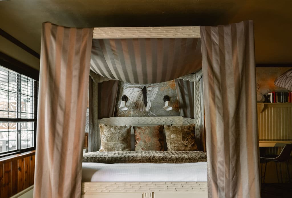 A cozy, canopy bed adorned with soft pillows and warm lighting in a stylish room.