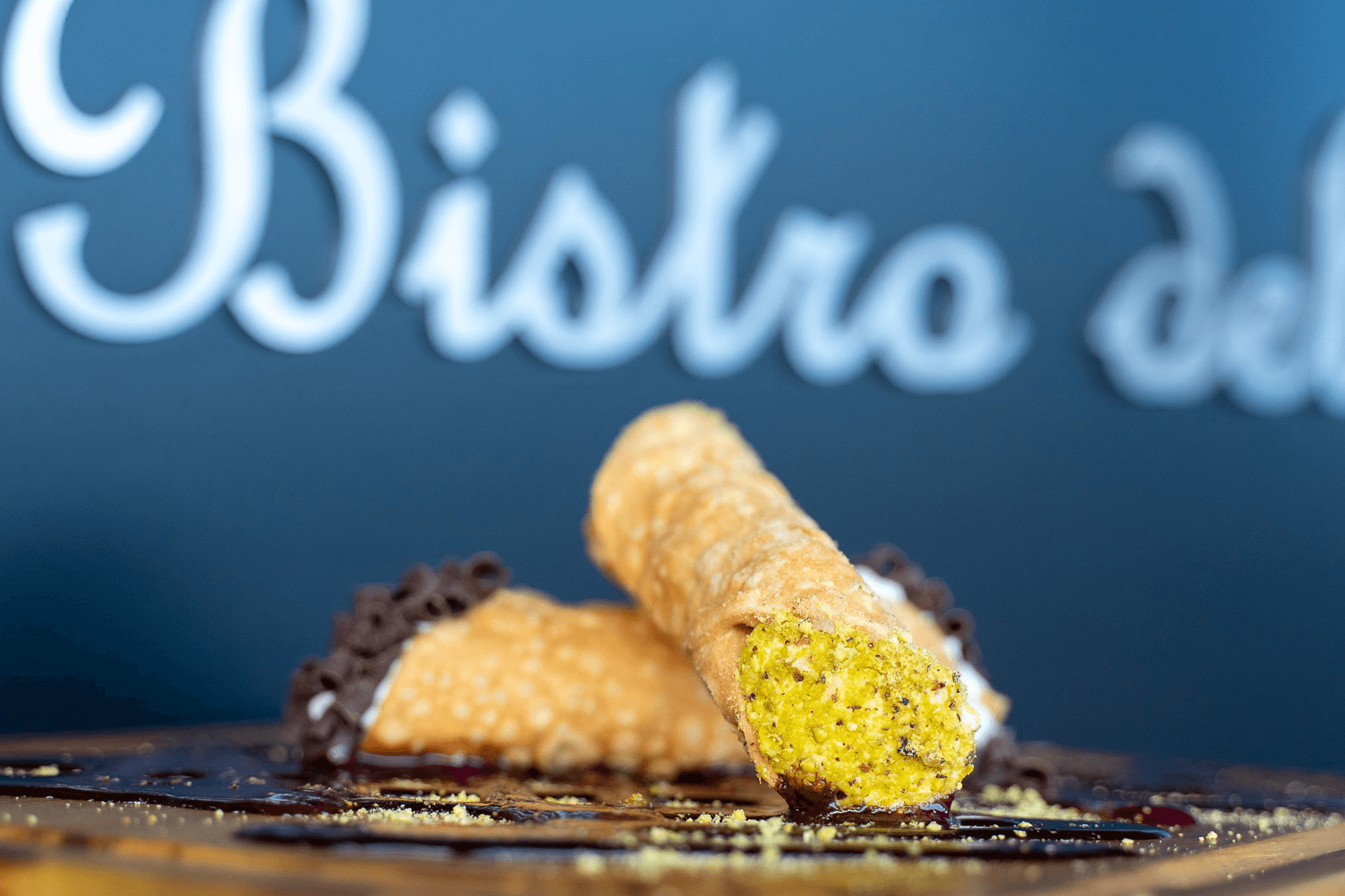 A close-up of a pistachio-filled cannoli on a dessert plate.
