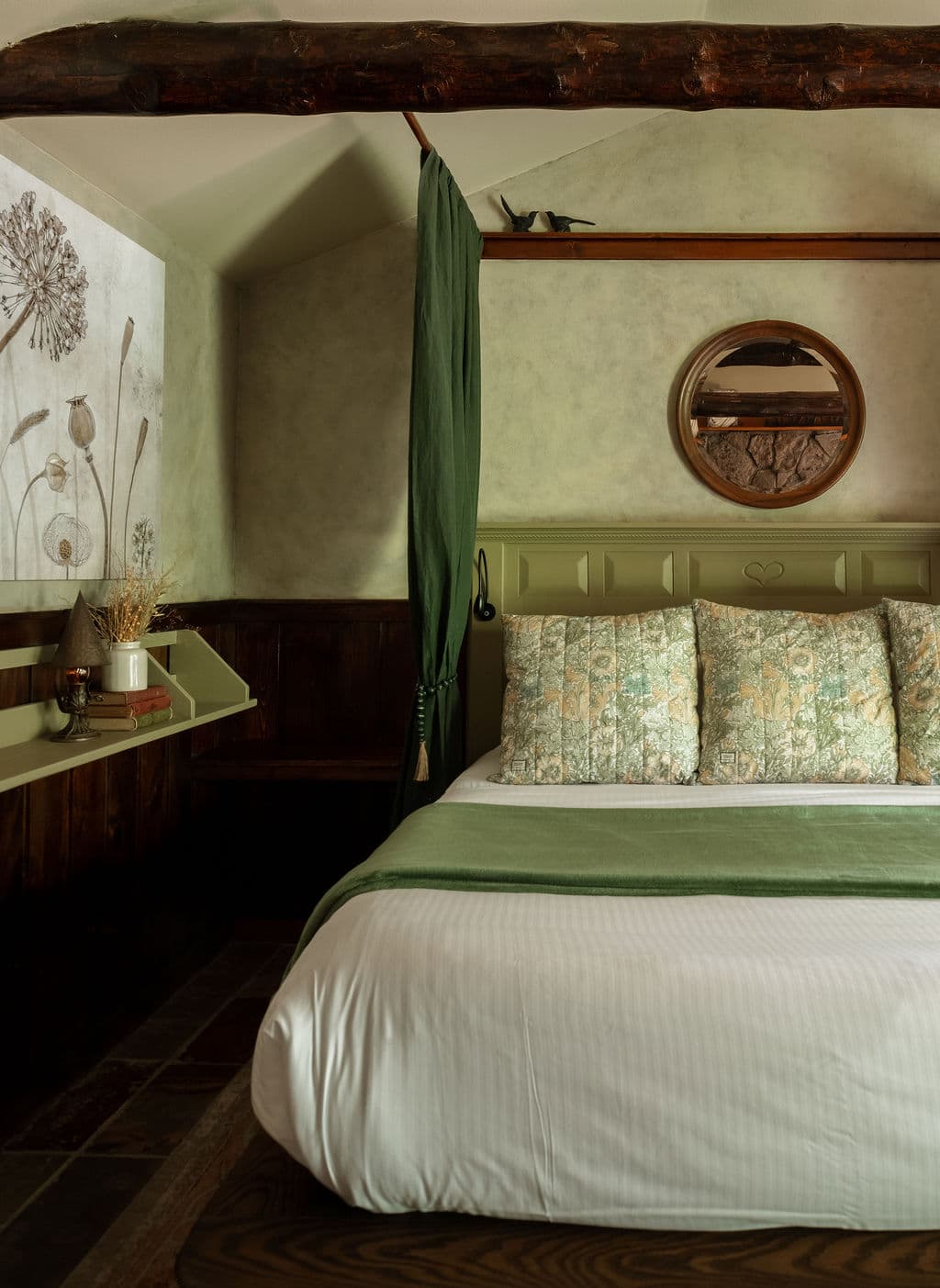 A cozy bedroom featuring a green and white color scheme, floral-patterned pillows, and rustic decor.