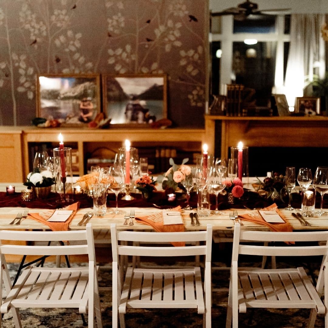 A beautifully set dinner table with candles and floral decor in a warmly lit room.