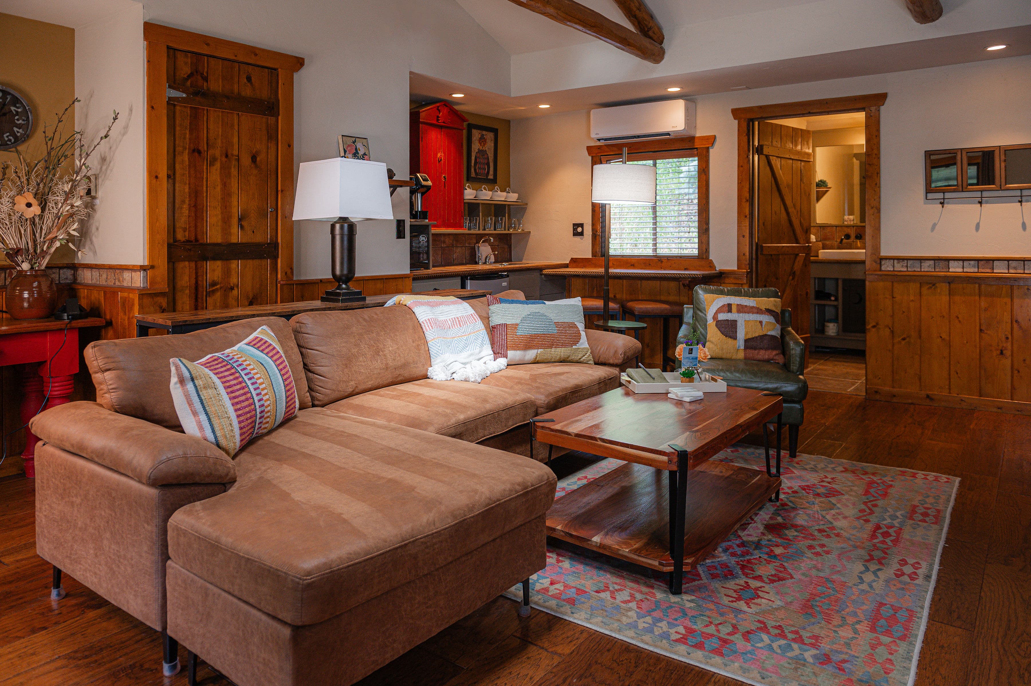 A cozy living room featuring a brown sectional sofa, wooden furniture, and warm decor.