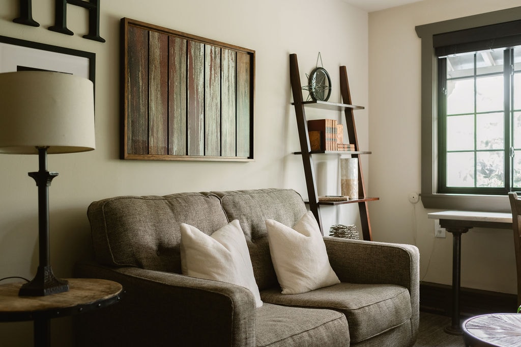 sitting room, red leather love seat, and round coffee table, desk with chair seat under picture window.