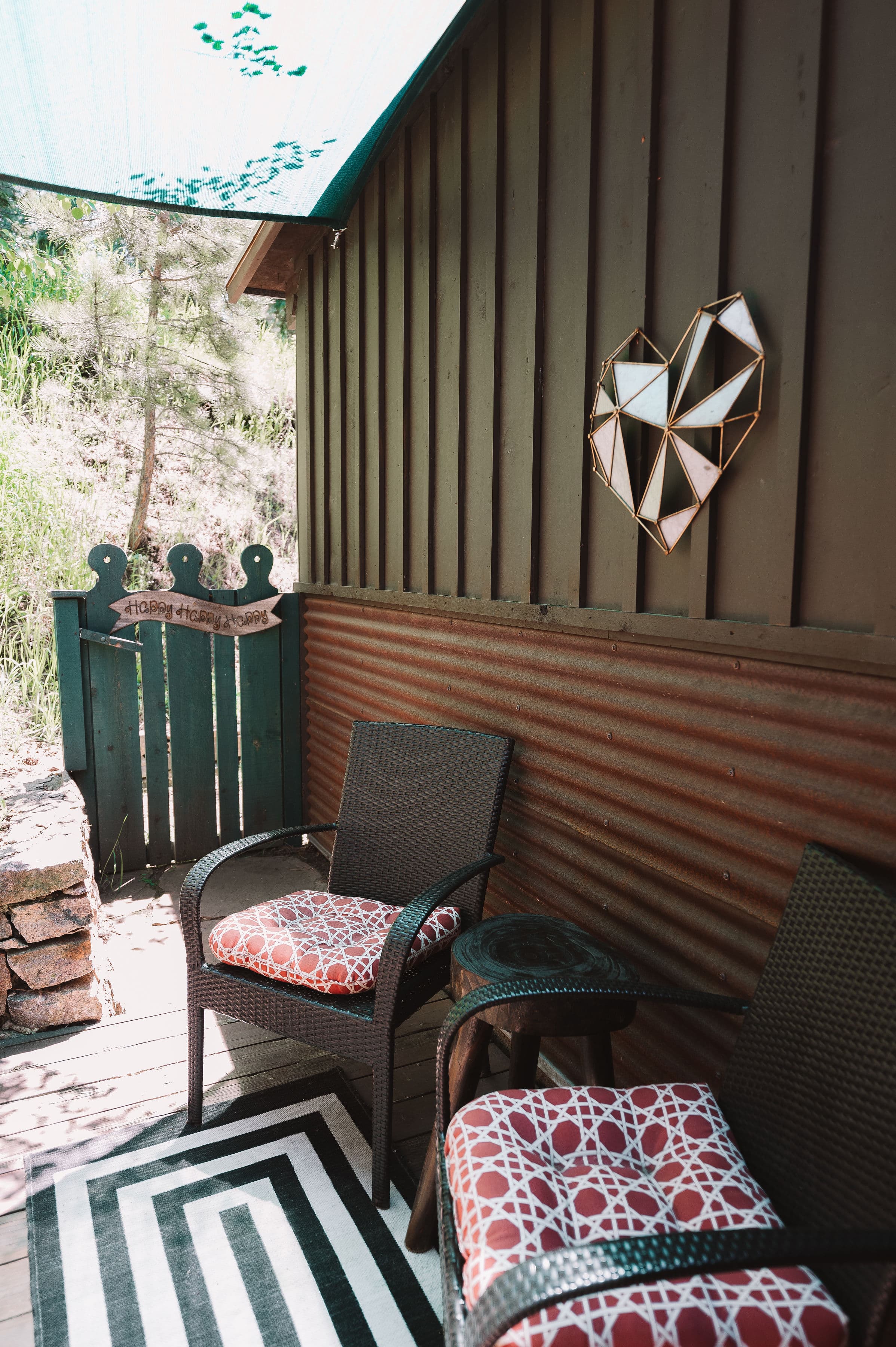 A cozy outdoor seating area with two wicker chairs and a geometric heart decoration on the wall.