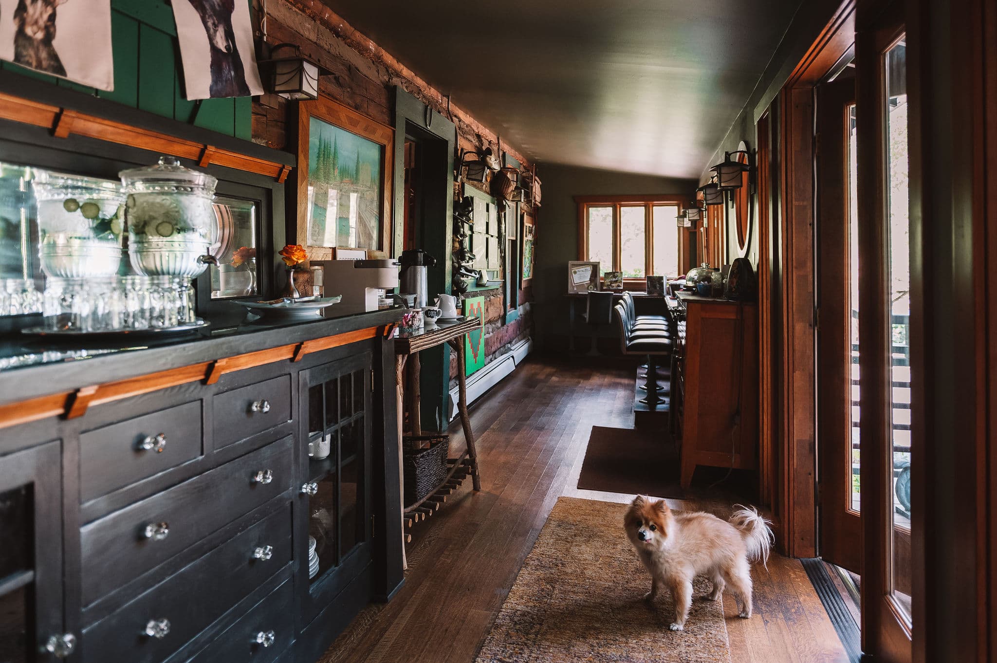 A cozy interior hallway featuring a Pomeranian dog and rustic wooden furnishings.