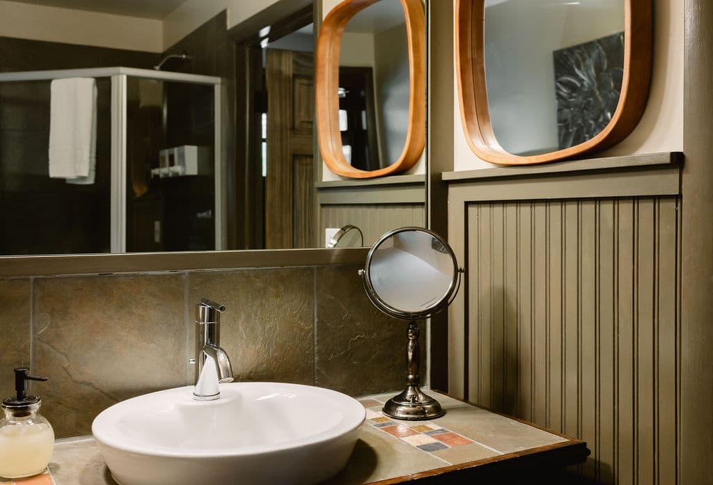 A modern bathroom featuring a white sink, decorative mirrors, and a shower in the background.