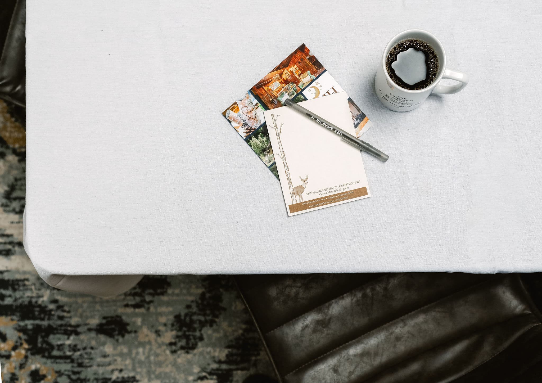 A white tablecloth with postcards, a pen, and a mug of coffee.