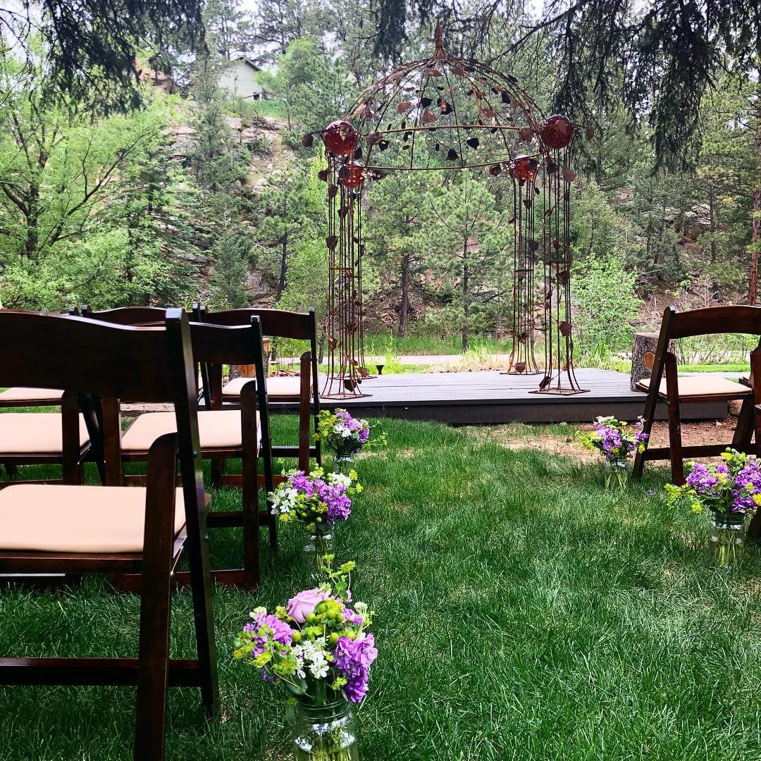 A beautiful outdoor wedding setup with chairs, floral arrangements, and a decorative arch.