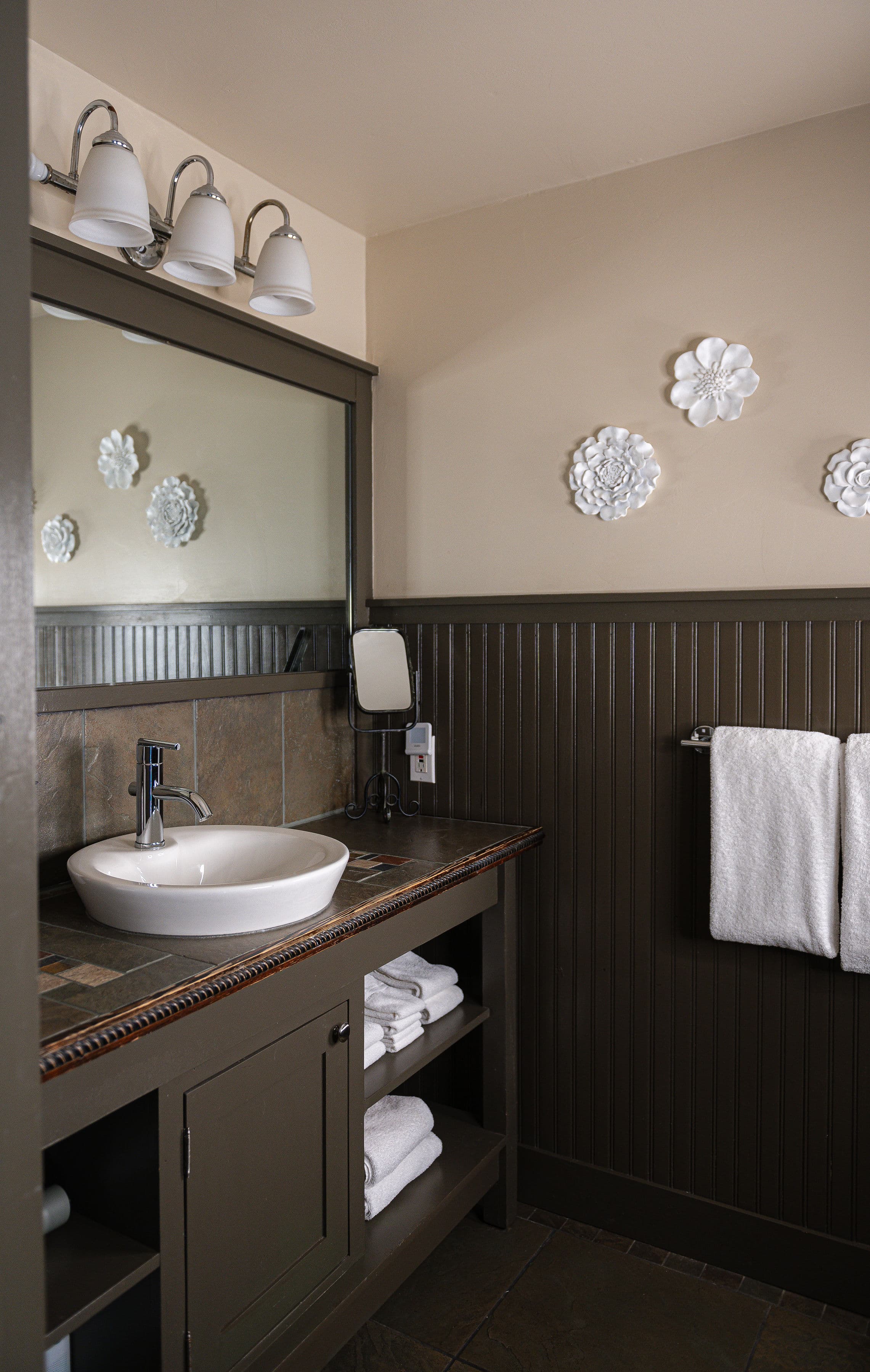 A well-decorated bathroom featuring a vanity with a sink, a mirror, and neatly arranged towels.