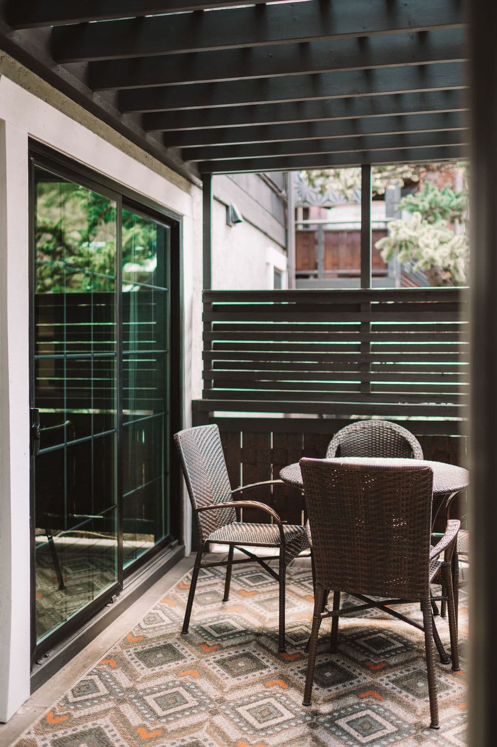 A cozy outdoor patio featuring a round table and two chairs beside sliding glass doors.