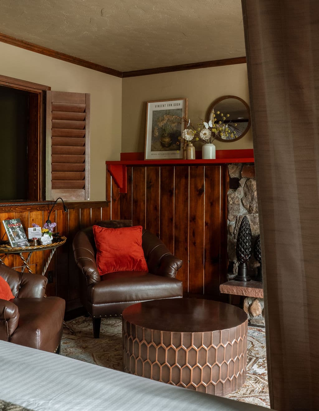 A cozy living space featuring two brown leather chairs, a honeycomb-patterned coffee table, and decorative accents on a wooden wall.