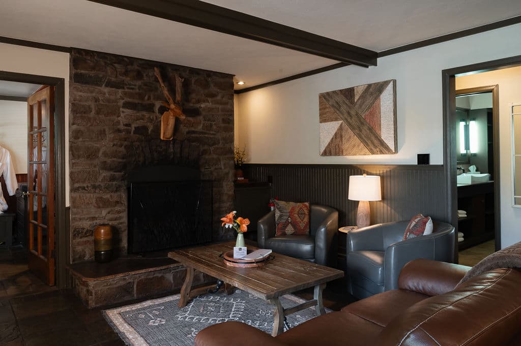 Cozy living room featuring a stone fireplace, comfortable seating, and modern art.