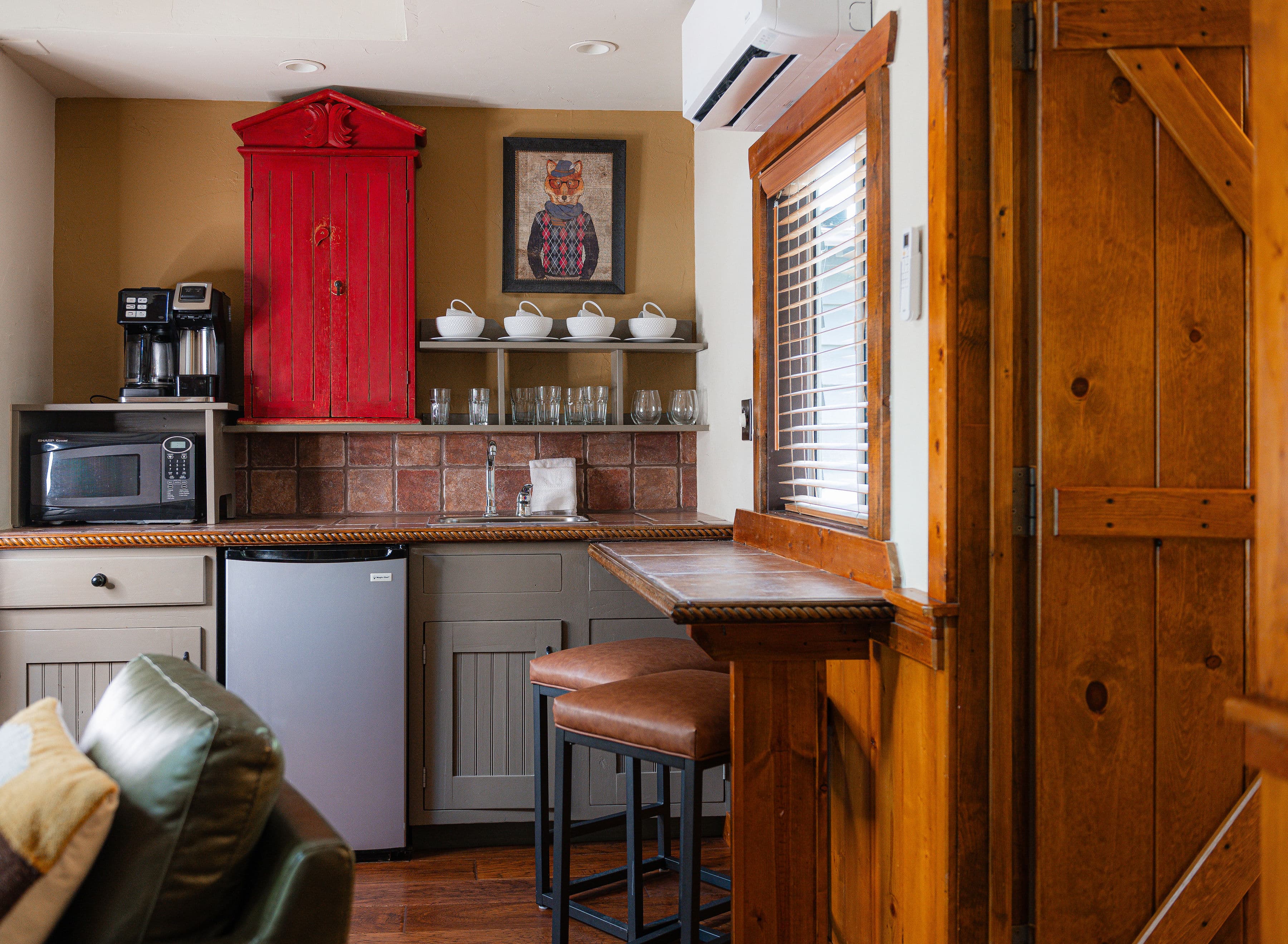 Cozy kitchen nook featuring a red cabinet, coffee maker, and bar seating.