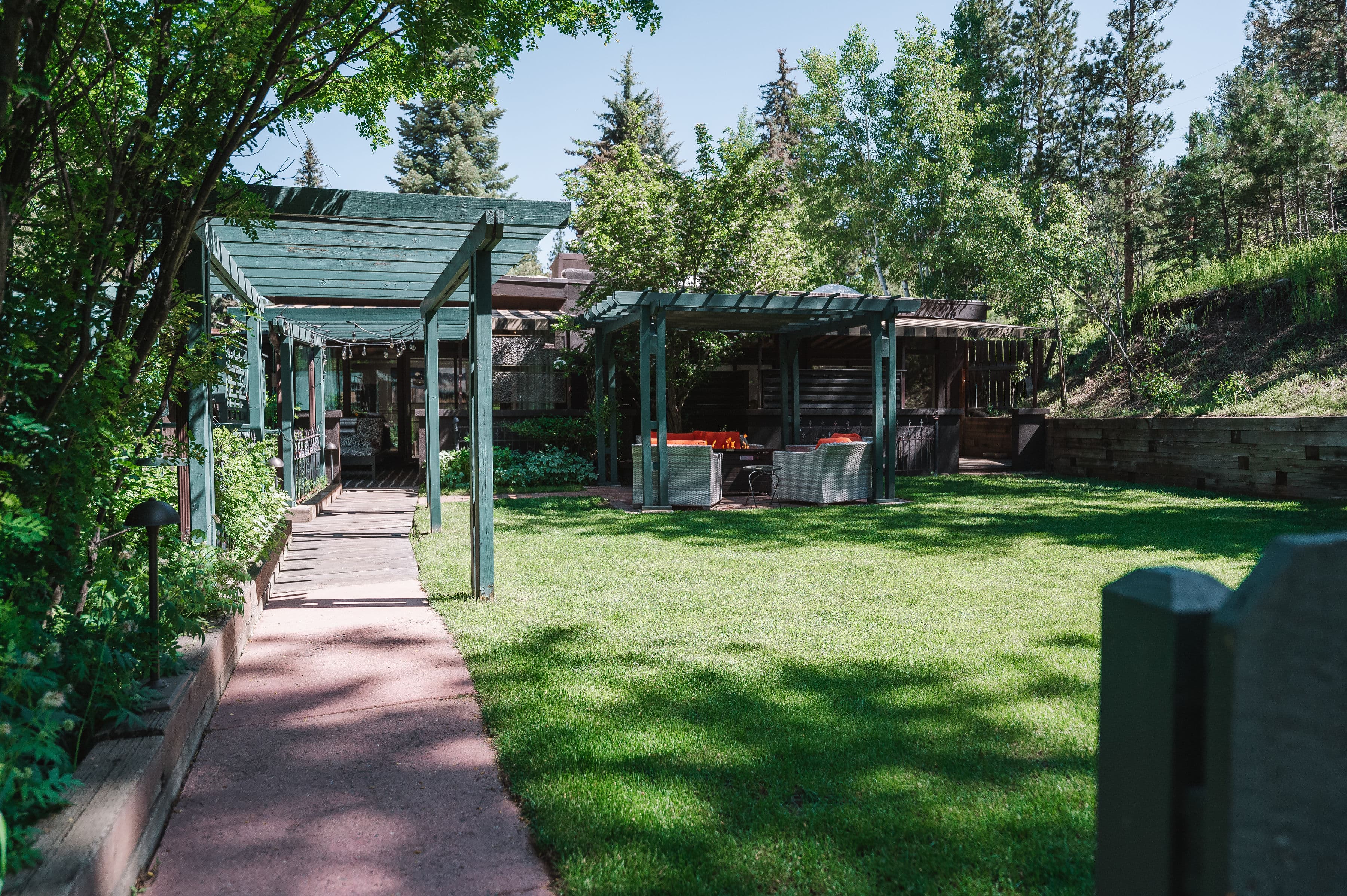 A serene garden path leads to a shaded seating area surrounded by greenery.