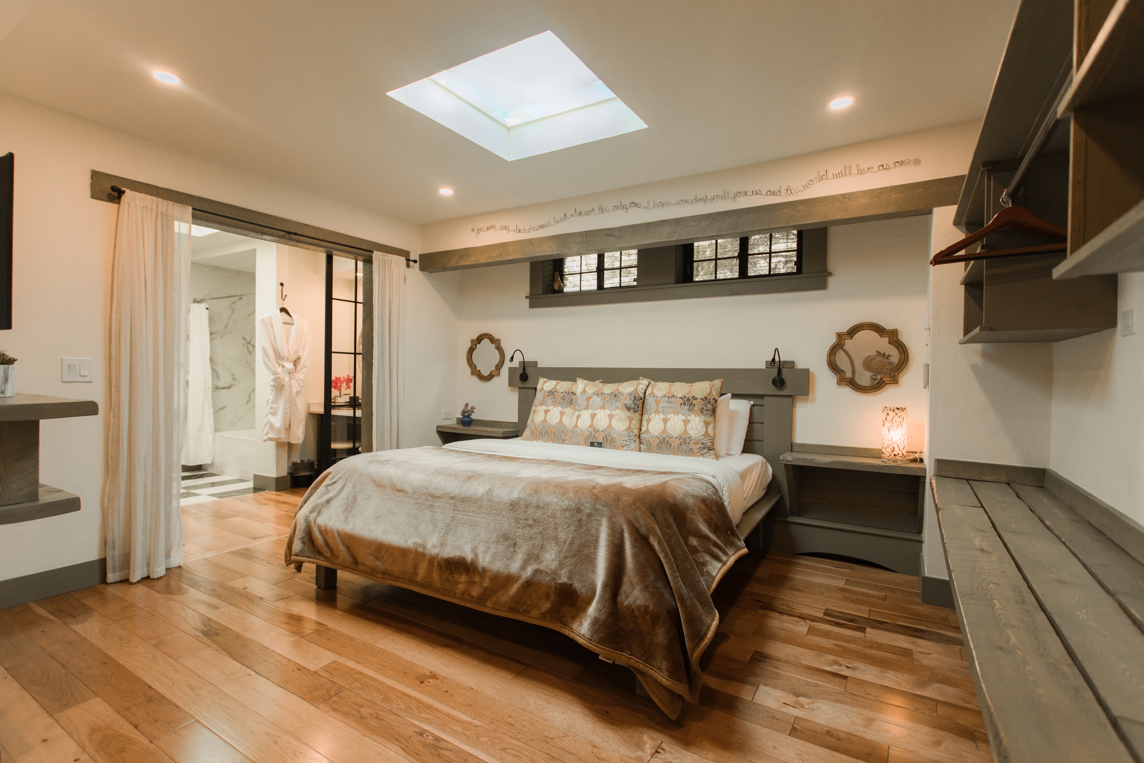 Cozy bedroom featuring a large bed, wooden floors, and a skylight.