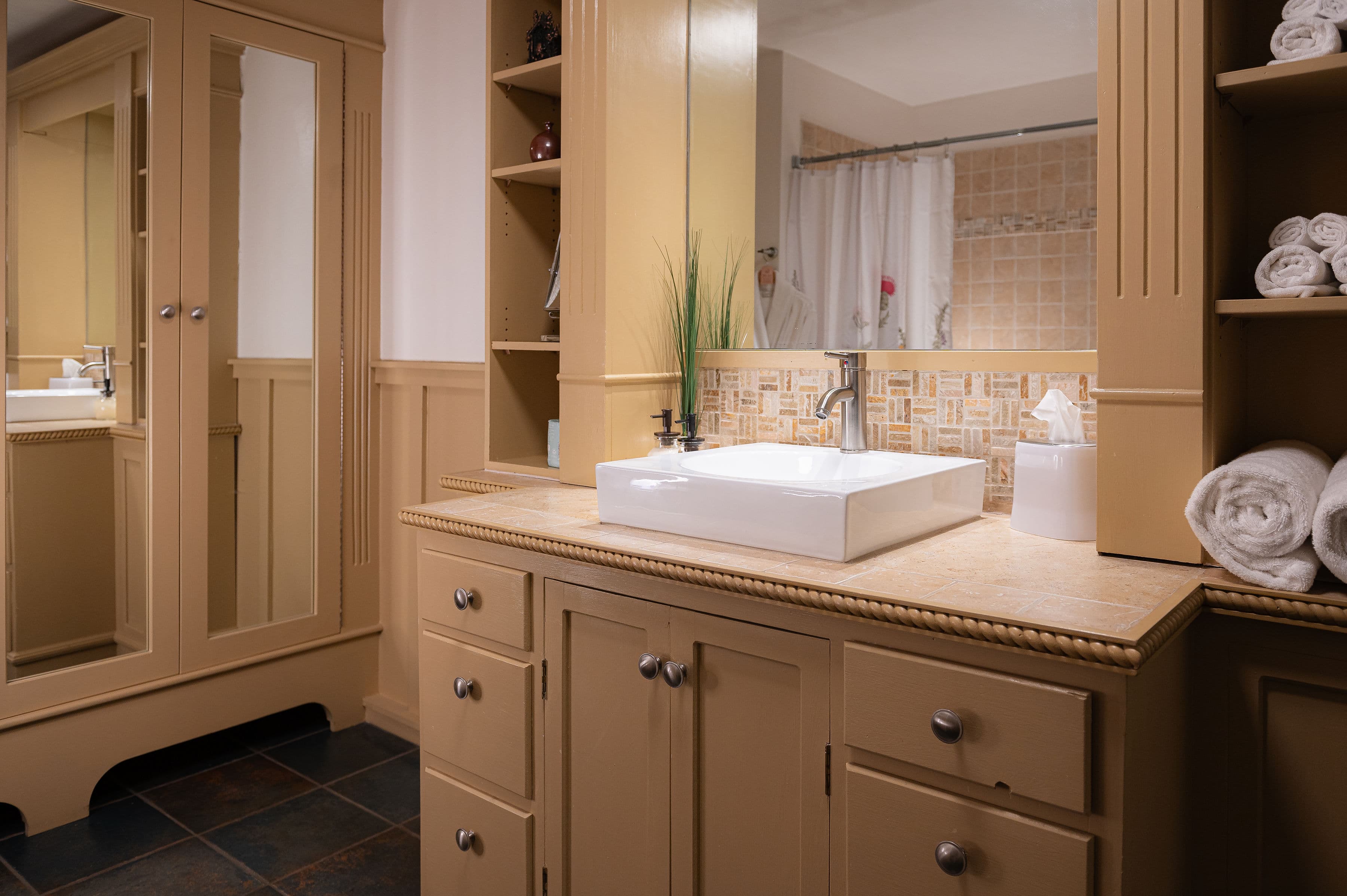 A well-lit bathroom featuring a modern sink, storage cabinetry, and neatly arranged towels.