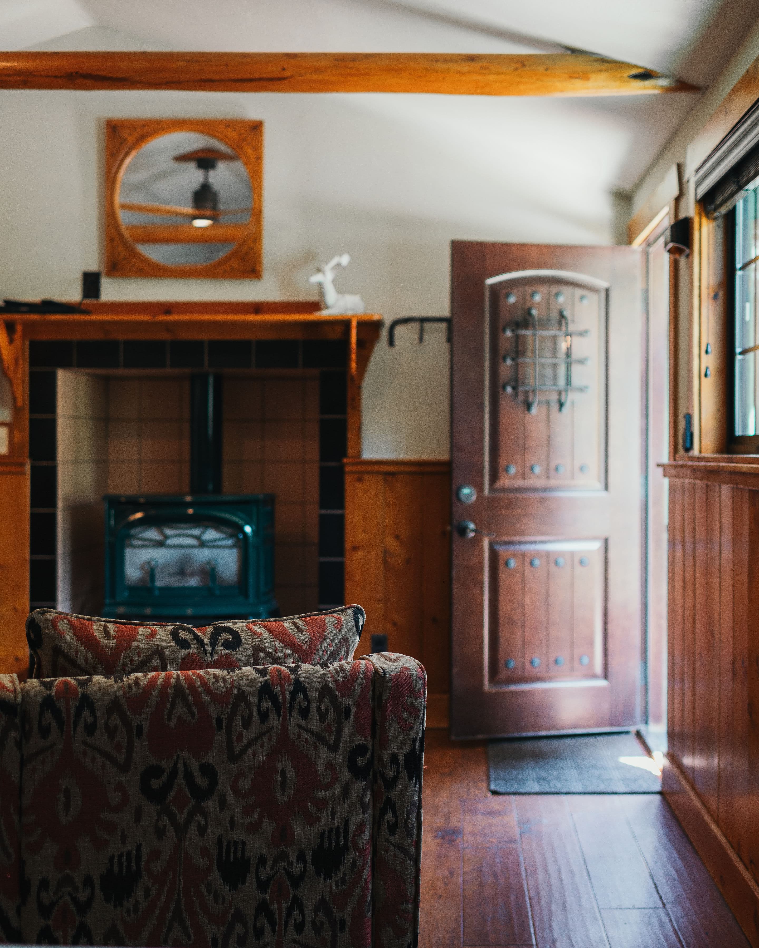 Cozy interior view of a room with a patterned chair, a fireplace, and an open wooden door.