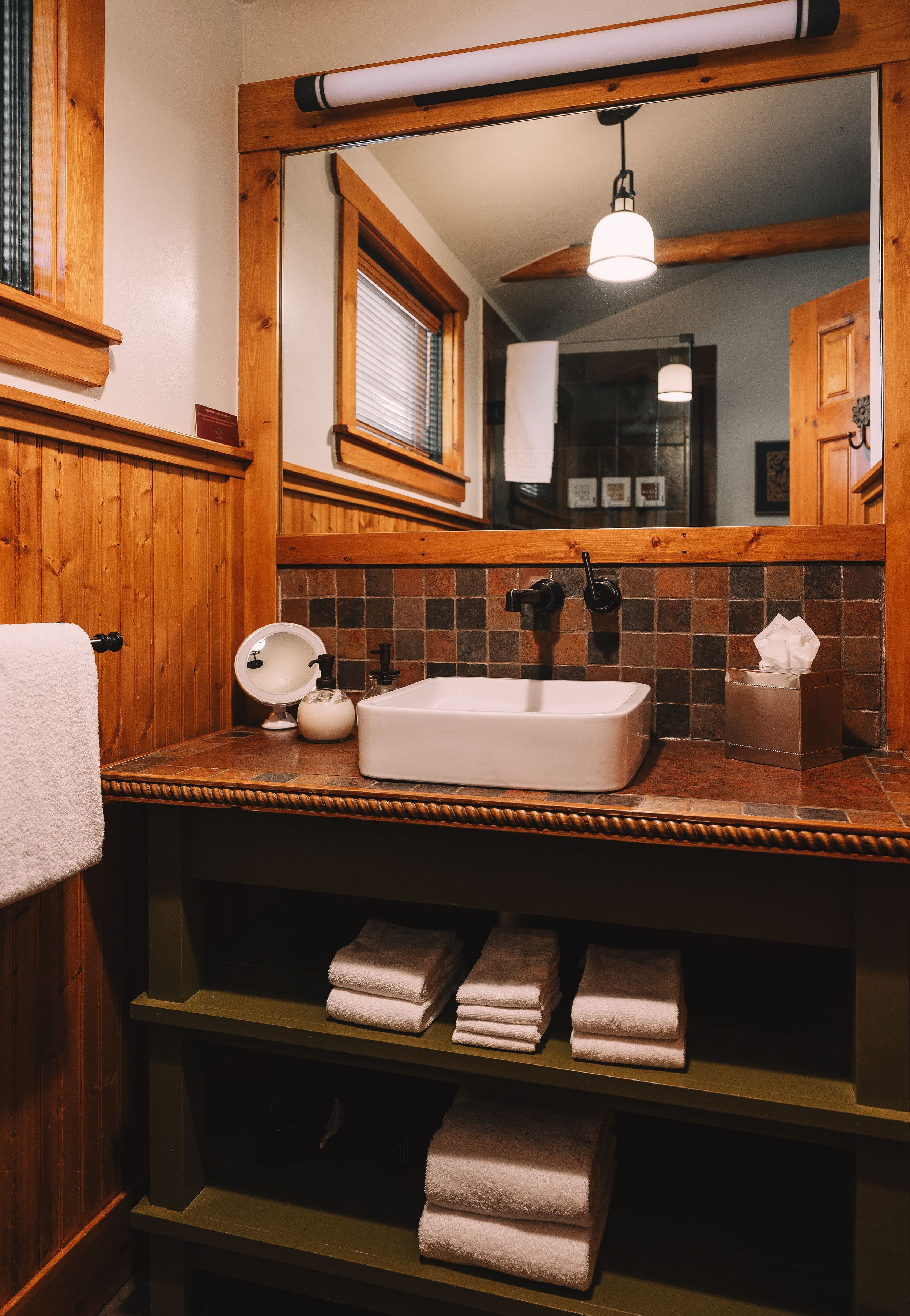 A cozy bathroom featuring a wooden sink countertop, a white sink, and neatly stacked towels.
